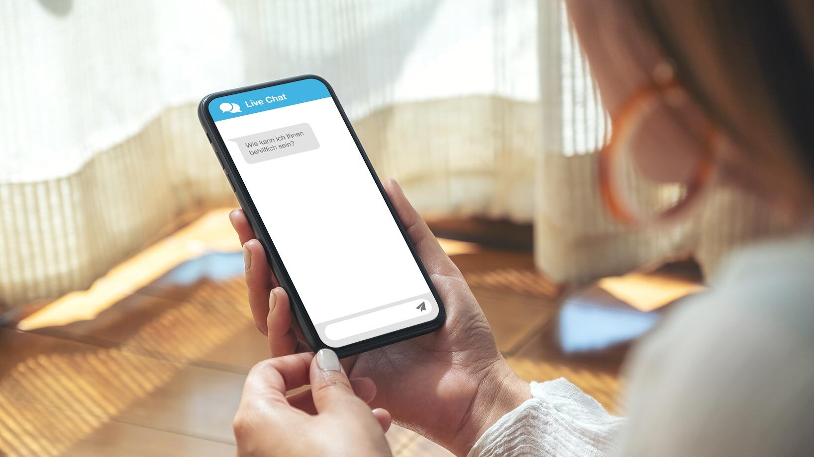 Eine Frau hält ein Smartphone in der Hand, auf dem ein Live-Chat-Fenster geöffnet ist.